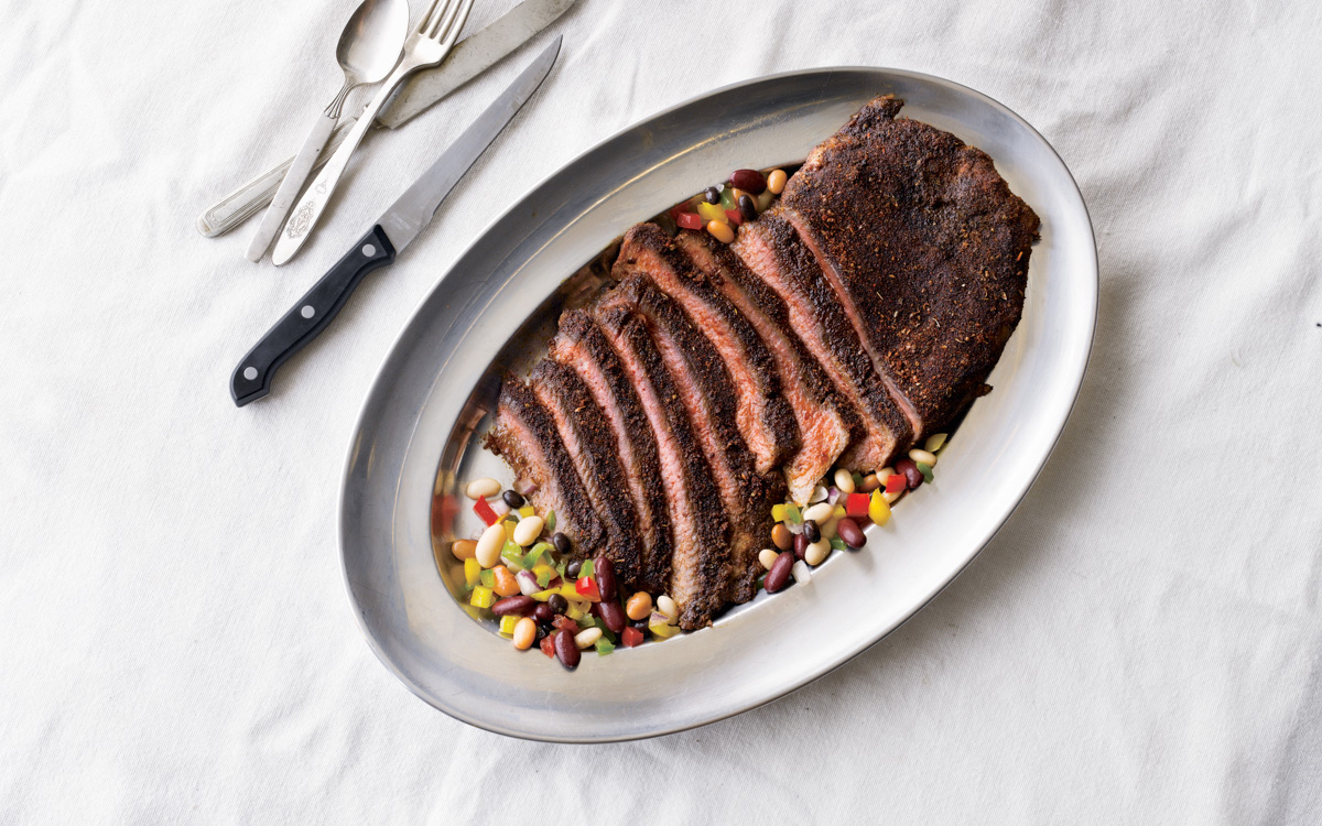 dry-rub steak on a platter with bean salad