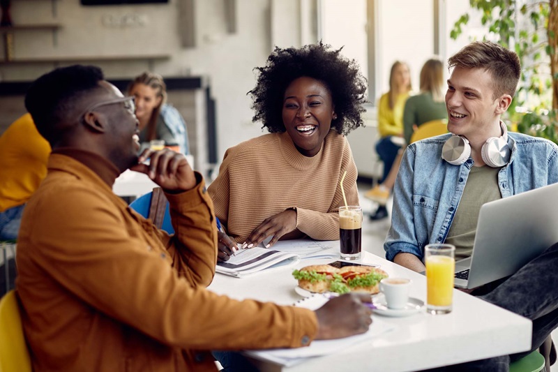 A young black man, black woman, and white man enjoying a meal