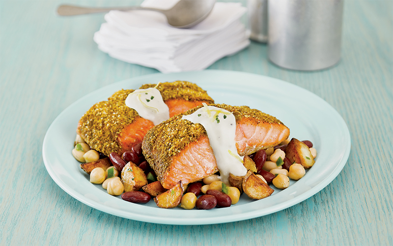 Plate with curried salmon topped with lemon-yogurt sauce on a bed of bean-potato hash.